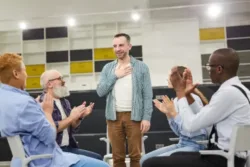 man introducing himself in a 12 step meeting other attendees clapping