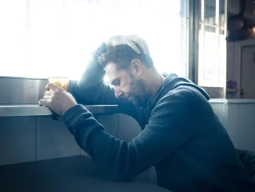 man resting his head on a windowsill in frustration