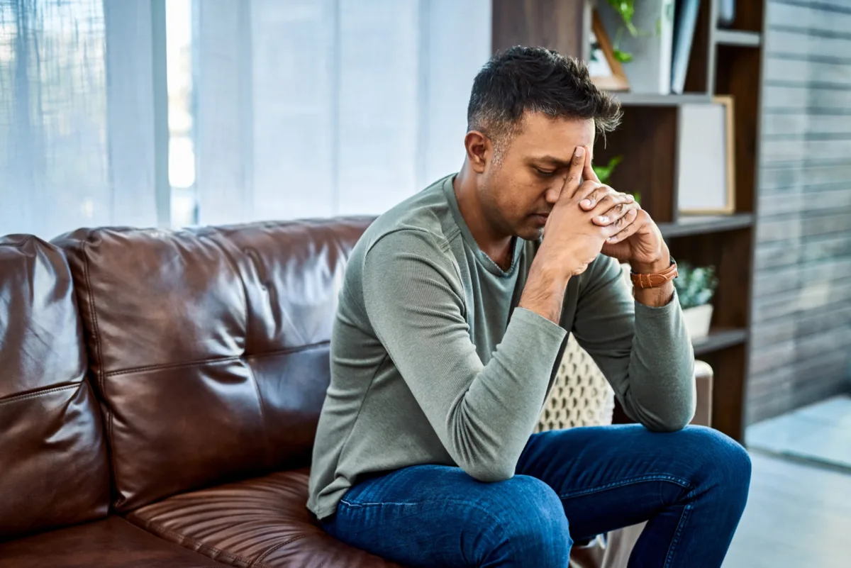 man looking stressed while sitting on couch at home