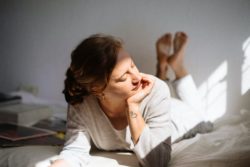 Woman laying on her bed with the sunlight shining on her face