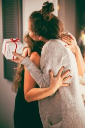 Girl friends exchanging gifts and hugging