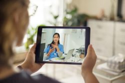 iStock-1062130130 Woman holding up her tablet for a telehealth call