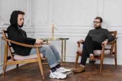 pexels-cottonbro-4100638 Abused teen with a black eye sitting in his doctors office with headphones on while his therapist/psychiatrist observes him