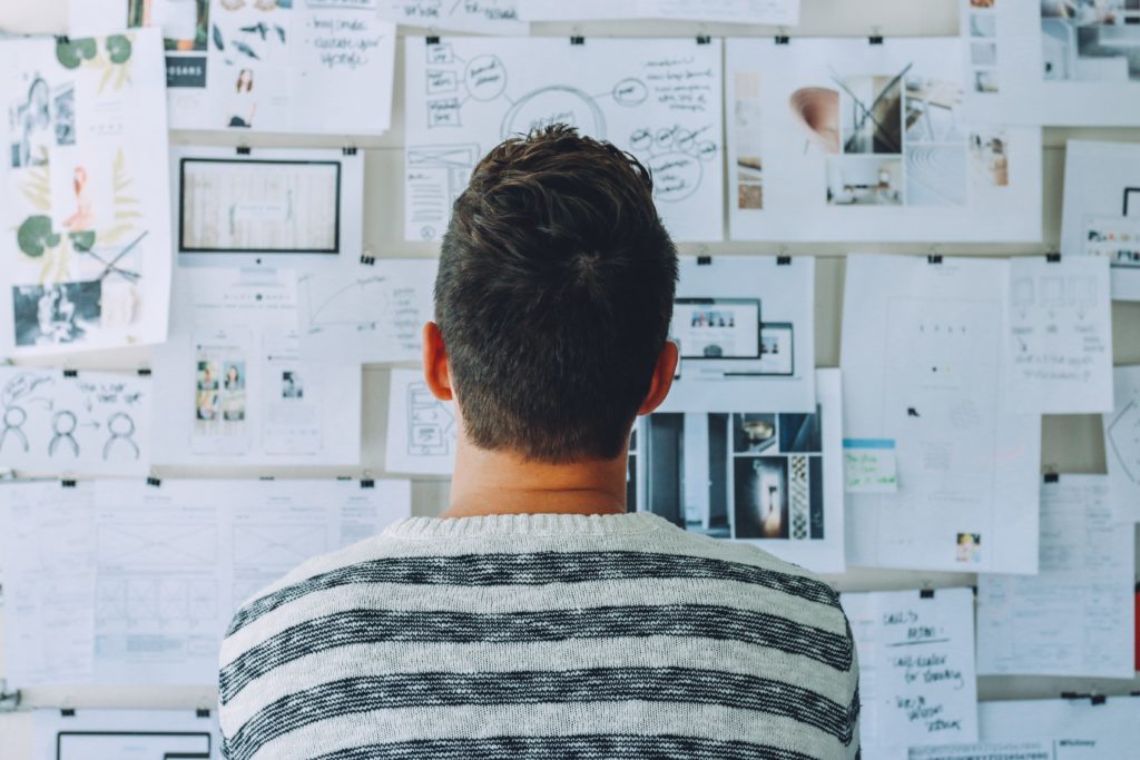 Man looking over work plans pinned to a board in front of him