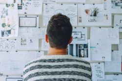 pexels-startup-stock-photos-212286 Man looking over work plans pinned to a board in front of him