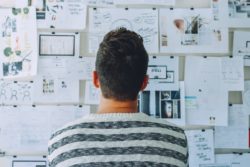 Man looking over work plans pinned to a board in front of him