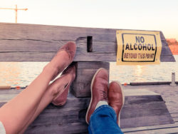 Concept of a young couple decided to stop consuming alcohol. Legs of a man and a women pointing to a sign ''No Alcohol beyond this point''