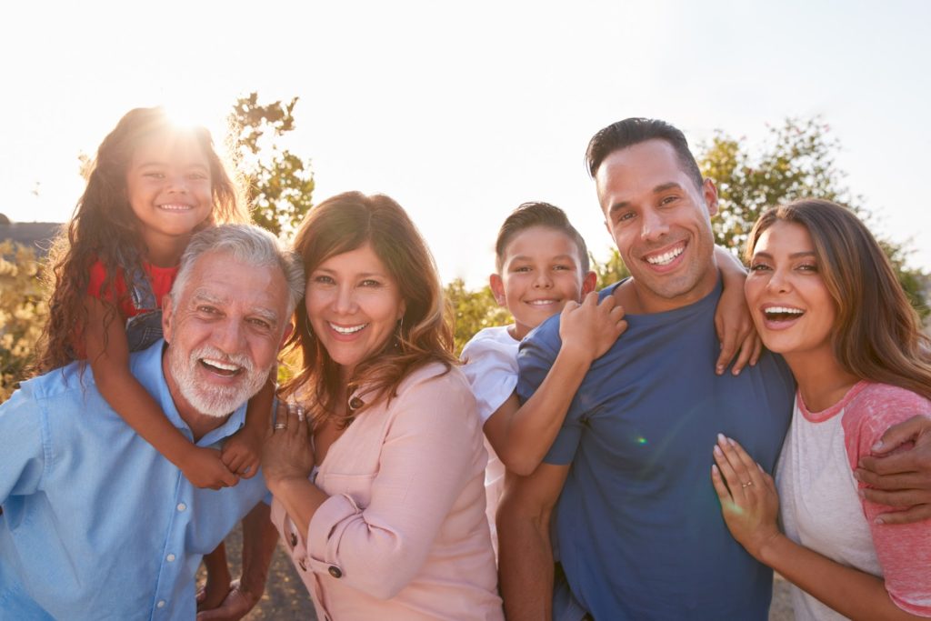 Portrait Of Multi-Generation Hispanic Family Relaxing In Garden At Home Together