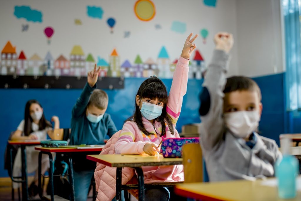 Elementary schoolchildren wearing a protective face masks in the classroom. Education during epidemic.