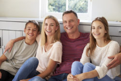 Portrait Of Smiling Family Relaxing On Seat At Home