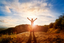 Silhouette of a man with hands raised in the sunset concept for religion, worship, prayer and praise