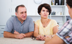 Serious mature couple having conversation with adult daughter at home