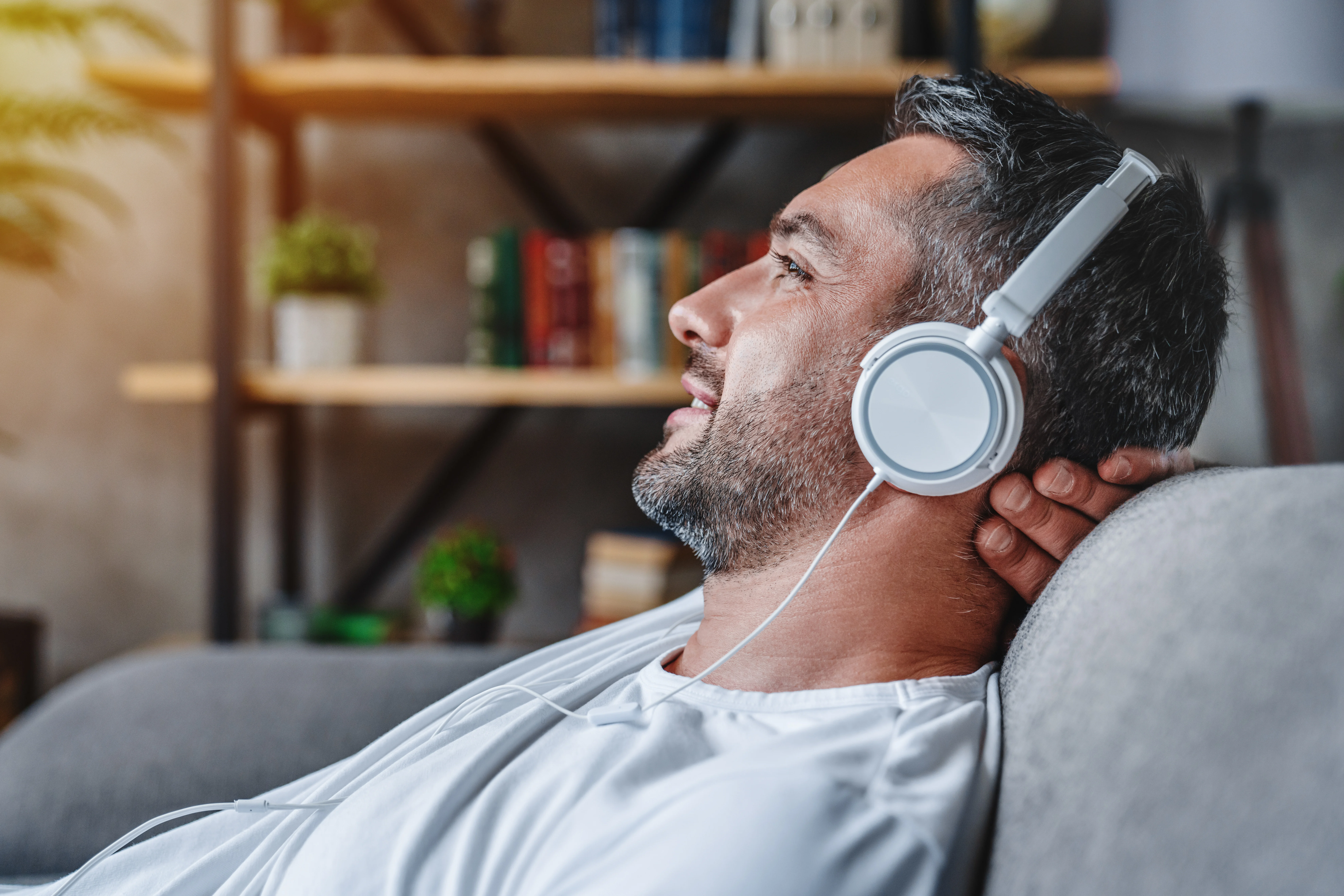 middle-aged-man-listening-music-with-headphones-relaxed-in-sofa-at-his-home-stockpack-istock Middle aged man listening music with headphones relaxed in sofa at his home