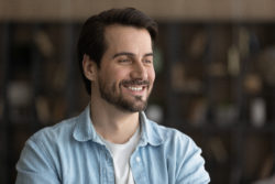 Close up of happy millennial Caucasian man look in distance thinking or dreaming of career perspectives. Smiling young male pondering planning or visualizing. Business vision, success concept.