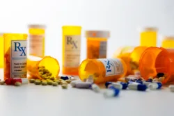 Prescription bottles and pills on a counter.