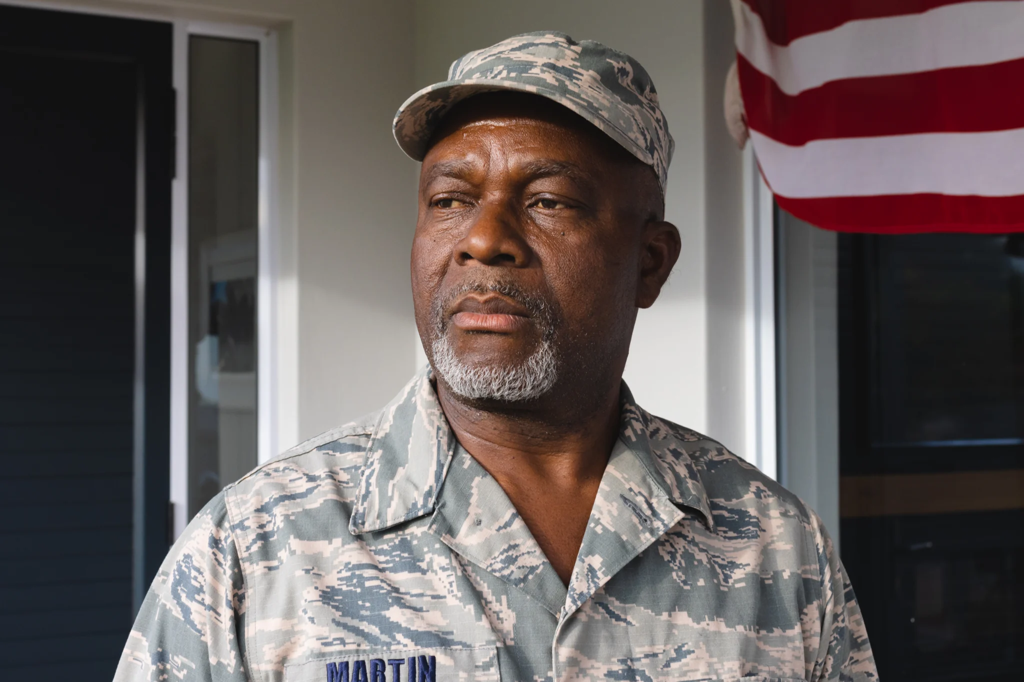 African american military senior man in camouflage clothing and cap looking away against house. Contemplation, unaltered, pride, military, armed forces, patriotism and homecoming concept.