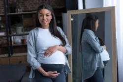 african american pregnant with big belly standing at mirror