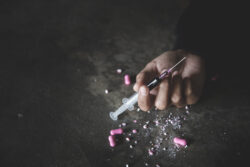 human-hand-of-a-drug-addict-and-a-syringe-with-narcotic-syringe-lying-on-the-floor-26-june-international-day-against-drug-abuse-stockpack-gettyimages