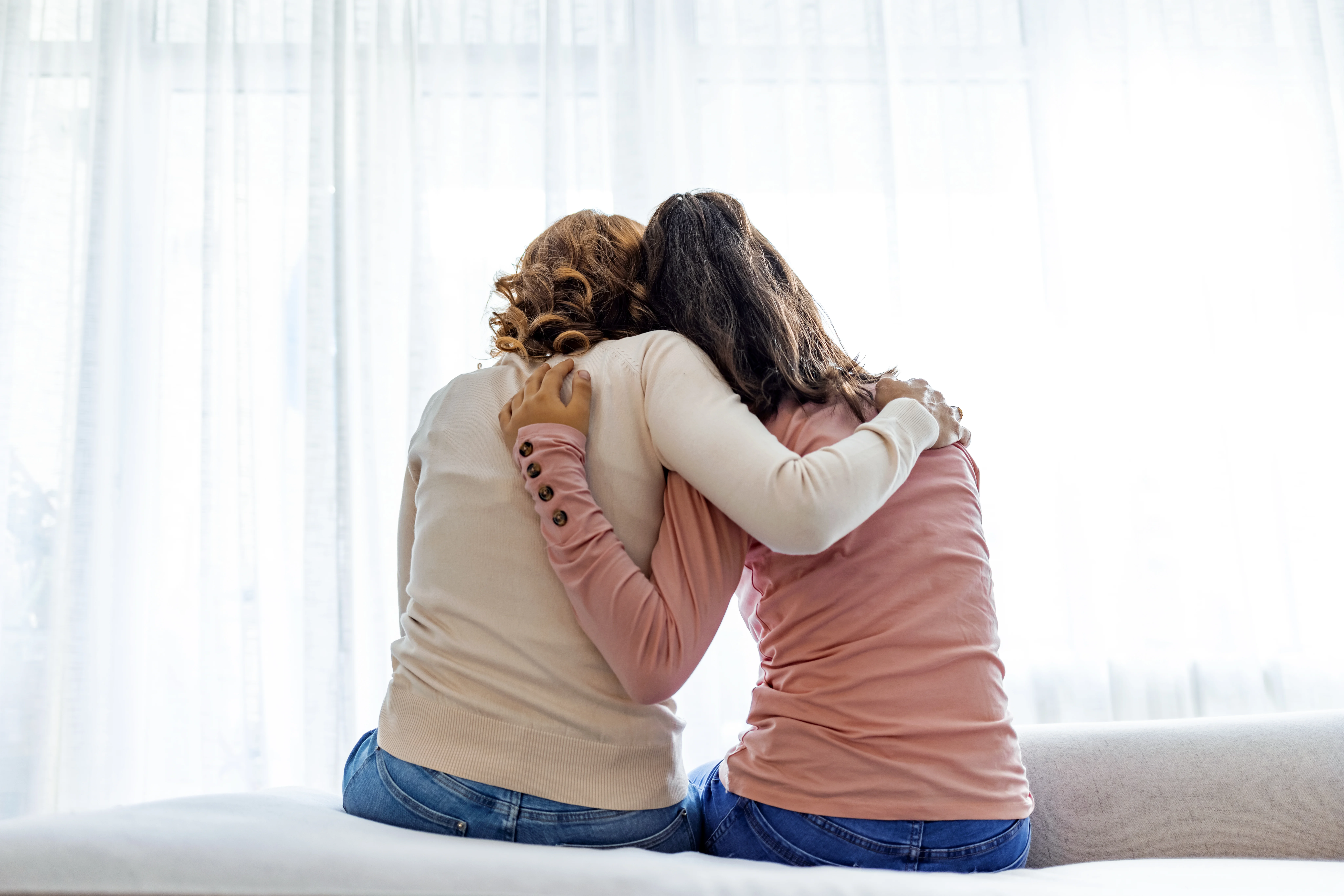 rear-back-view-of-a-mother-and-daughter-embrace-sitting-on-bed-at-home-older-sister-consoling-younger-teen-girl-suffers-from-unrequited-love-share-secrets-trustworthy-person-relative-people-concept-stockpack-gettyimages Rear back view of a mother and daughter embrace sitting on bed at home, older sister consoling younger teen, girl suffers from unrequited love share secrets trustworthy person relative people concept