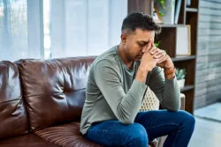 Shot of a man looking stressed while sitting on the sofa at home