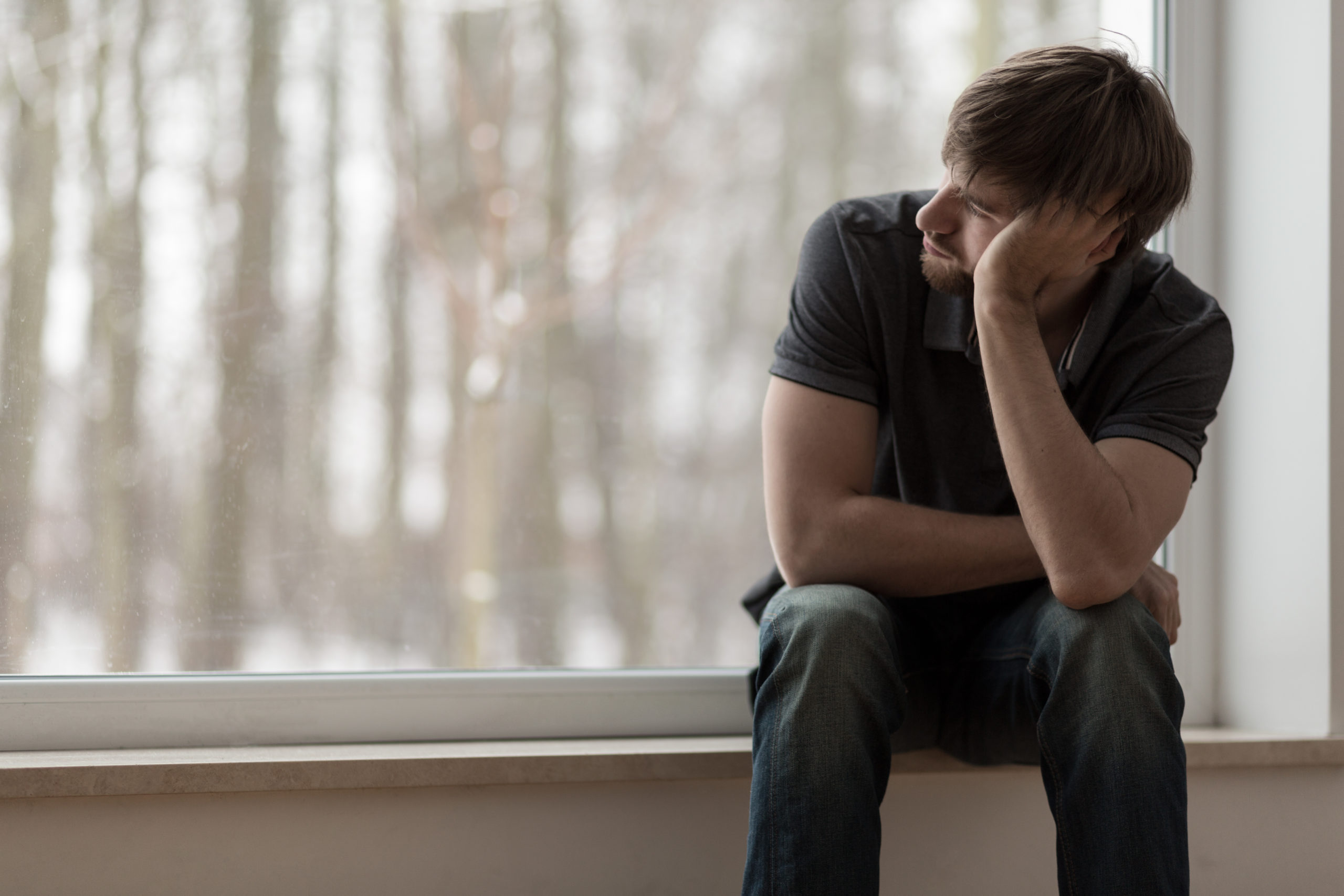 Young miserable depressed man sitting and thinking