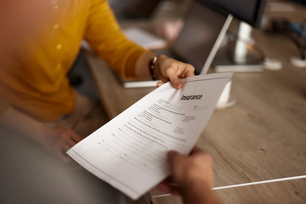 Close up of unrecognizable woman taking insurance report from her colleague in the office.